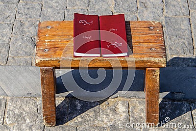 Two korans sitting on a grungy wooden table on cobblestone surface in sun with shadow Editorial Stock Photo