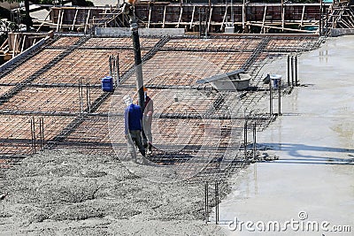 two labor work pouring liquid concrete from cement mixer to building floor in construction site Stock Photo