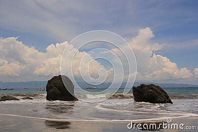 TWO LARGE ROCK ADORN THE BEACH WITH A CLOUDY BLUE SKY CREATING A C HARMING ATMOSPHERE Stock Photo