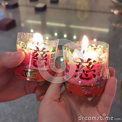Two lit chinese praying candle for Chinese new year celebration held by couple lovers Stock Photo