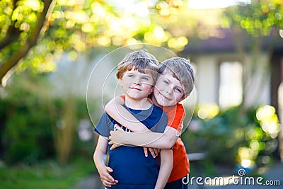 Two little active school kids boys, twins and siblings hugging on summer day Stock Photo