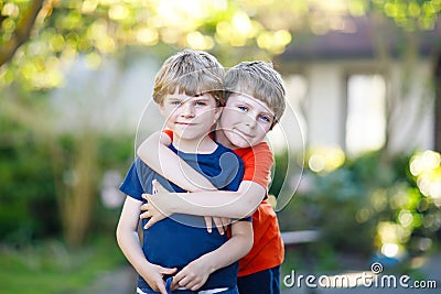 Two little active school kids boys, twins and siblings hugging on summer day Stock Photo