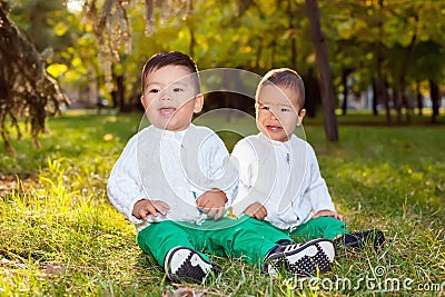 Two little Asian child playing in the Park, sitting on the grass Stock Photo