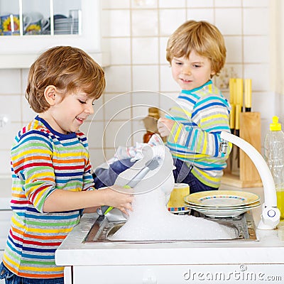 Two little blond kid boys washing dishes in domestic kitchen Stock Photo