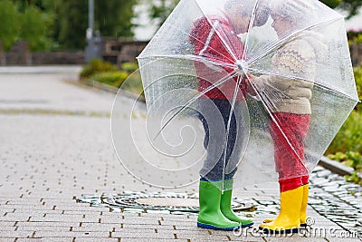 Two little boys, best friends and siblings walking with big umbrella outdoors on rainy day. Preschool children having Stock Photo