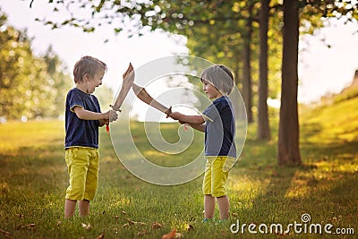 Two little boys, holding swords, glaring with a mad face at each Stock Photo