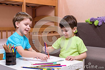 Two little caucasian friends playing with lots of colorful plastic blocks indoor. Active kid boys, siblings having fun building an Stock Photo