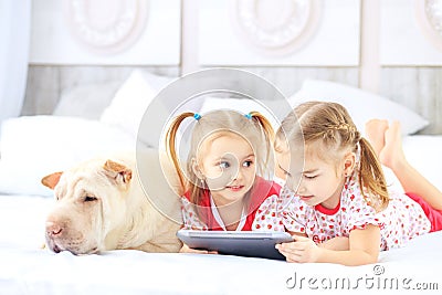 Two little children girls watching cartoons on the tablet. Dog. Stock Photo