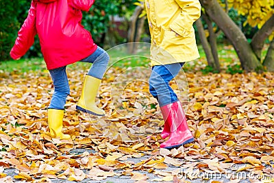 Two little children playing in red and yellow rubber boots in autumn park Stock Photo