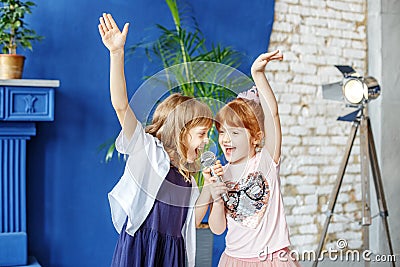 Two little funny children dance and sing a song in karaoke. The Stock Photo