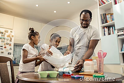 Two little girls feeling excited while cooking with their father Stock Photo