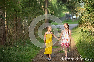 Two little girls go for the handle on the green alley. Walking. Stock Photo