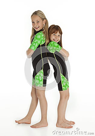 Two Little Girls Standing Back to Back Wearing Wetsuits Stock Photo
