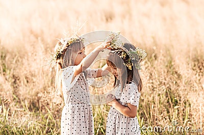 Two little happy identical twin girls playing together in nature in summer. Girls friendship and youth concept. Active children`s Stock Photo