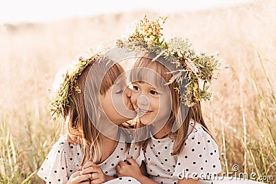 Two little happy identical twin girls playing together in nature in summer. Girls friendship and youth concept. Active children`s Stock Photo