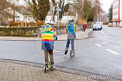 Two little kid boys, best friends riding on scooter in the city Stock Photo