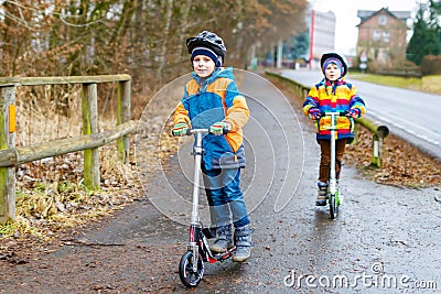 Two little kid boys, best friends riding on scooter in the city Stock Photo