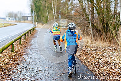 Two little kid boys, best friends riding on scooter in park Stock Photo