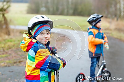 Two little kid boys, best friends riding on scooter in park Stock Photo