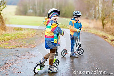 Two little kid boys, best friends riding on scooter in park Stock Photo