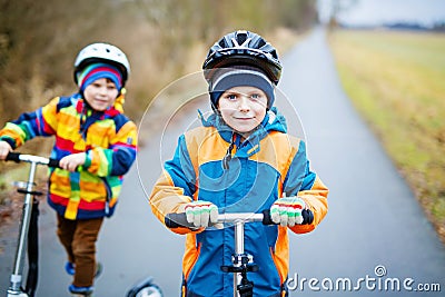 Two little kid boys, best friends riding on scooter in park Stock Photo