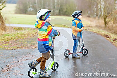 Two little kid boys, best friends riding on scooter in park Stock Photo