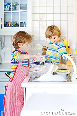 Two little kid boys washing dishes in domestic kitchen Stock Photo