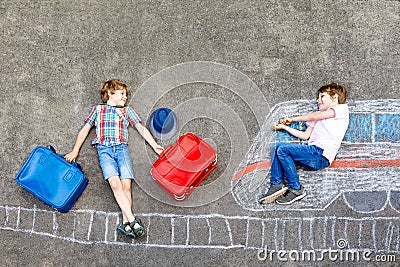 Two little kids boys having fun with train picture drawing with colorful chalks on ground Stock Photo