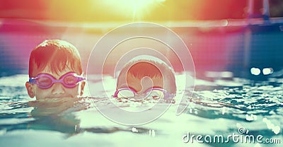 Two little kids in goggles swimming in pool at sunset Stock Photo