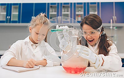 Two little kids in lab coat learning chemistry in school laboratory. Young scientists in protective glasses making Stock Photo