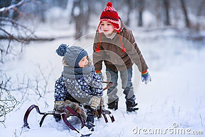 Two little preschool boys sledding in the snow Stock Photo