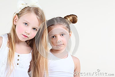 Two little serious girl in white clothes look at camera Stock Photo