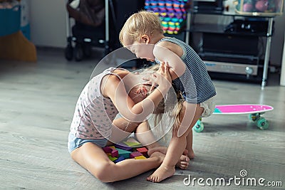 Two little siblings children quarrelling after playing at room at house. Crying offended toddler boy arguing with elder sister. Stock Photo