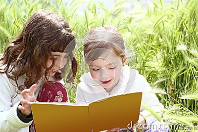 Two little sister girls reading book spikes garden Stock Photo