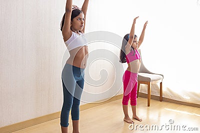 Two little sisters are doing exercise routines in the living room Stock Photo