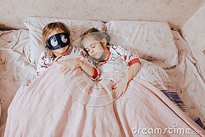 Two little sisters dressed in pajamas sleeping in the bed in the bedroom Stock Photo