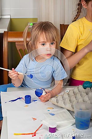 Two little sisters painting on Easter eggs Stock Photo