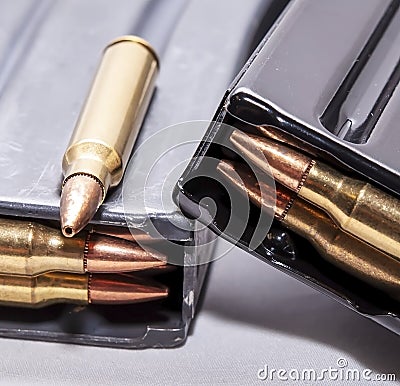 Two loaded rifle magazines with a 223 caliber bullet on top of one of them Stock Photo