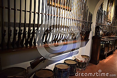Two long racks attached to a wall support dozens of ancient rifles of various sizes. Editorial Stock Photo