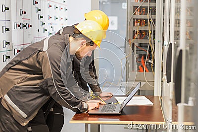 Two maintenance engineers inspect relay protection system with l Stock Photo