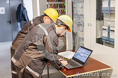 Two maintenance engineers inspect relay protection system with l Stock Photo