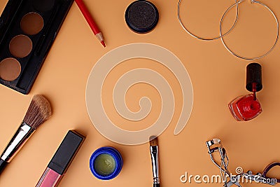 Two makeup brushes, brushes for blush, eyeshadow, pink lipstick, lip gloss, eyelash curler, round earrings, red lip pencil and Stock Photo