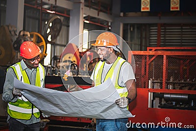 Two male African American maintenance engineers, are working and looking at blueprint Stock Photo