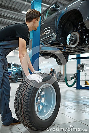 Two male mechanics fixes wheel, car service Stock Photo