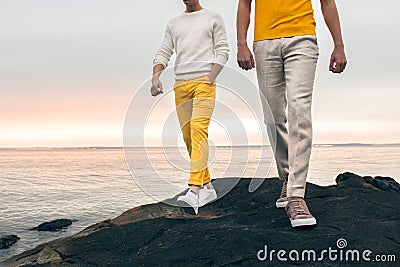 Two male models wearing fashionable spring summer outfit with colorful pants, t-shirt, sweater and shoes walking outdoors Stock Photo