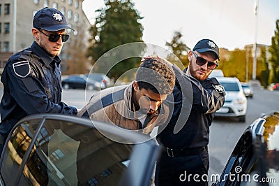 Two male police officers arrest young man Stock Photo