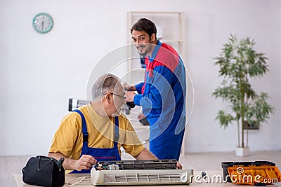 Two male repairmen repairing air-conditioner Stock Photo
