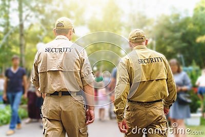 Two male security guards on public event among blurred background of many people on sunny street Editorial Stock Photo