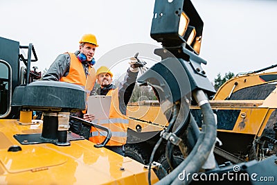 Two male workers on excavator in digging operation or quarry Stock Photo