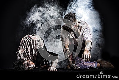Two male zombies crawling on their knees, on black smoky background Stock Photo